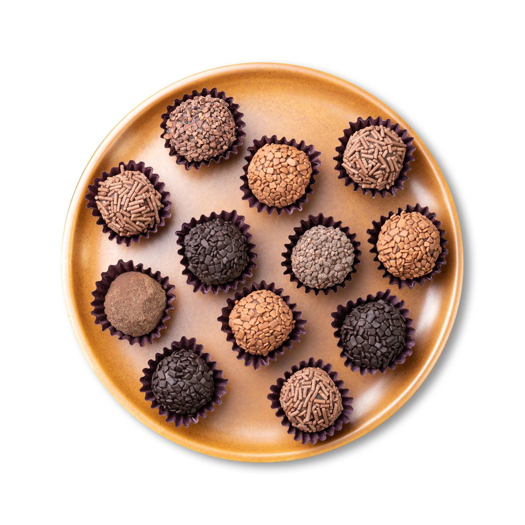Brigadeiros de varios sabores en plato, fondo blanco